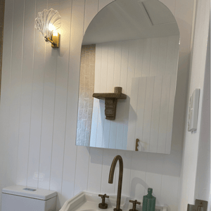 glass clamshell light switched on in bathroom with white VJ panelling
